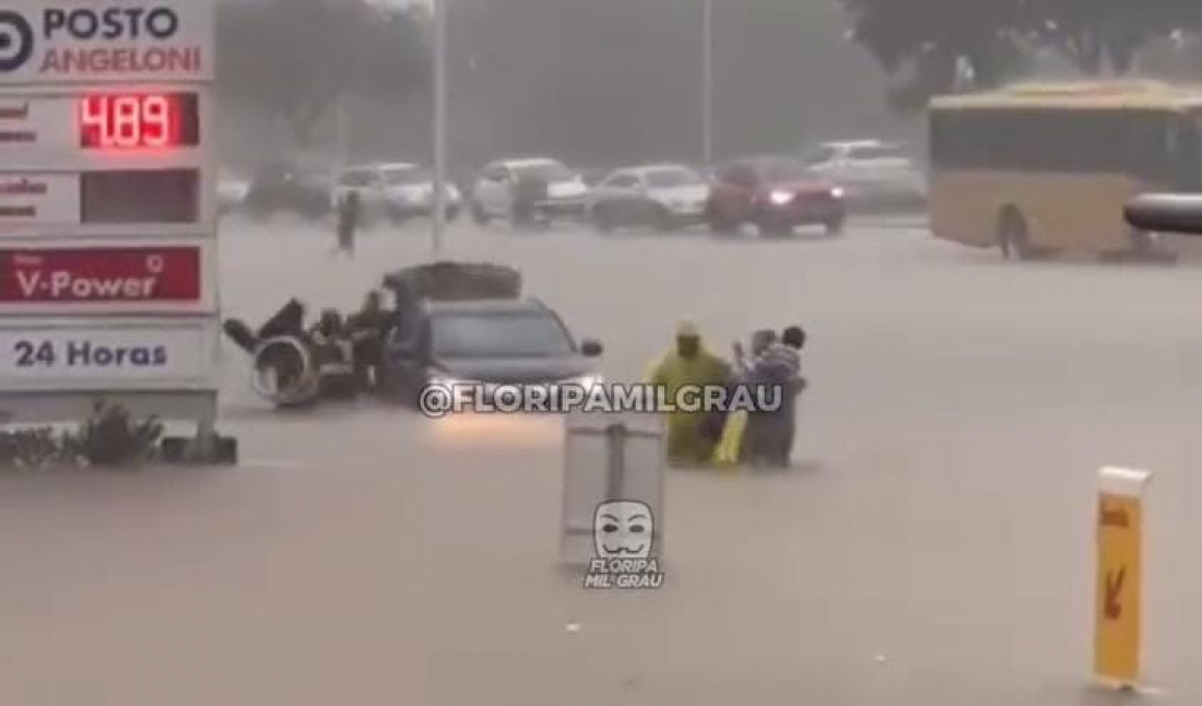 Homens auxiliam cadeirante a sair de carro na Beira-Mar Norte durante alagamento
